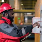 A fire alarm specialist in uniform checking the fire alarm system panel.